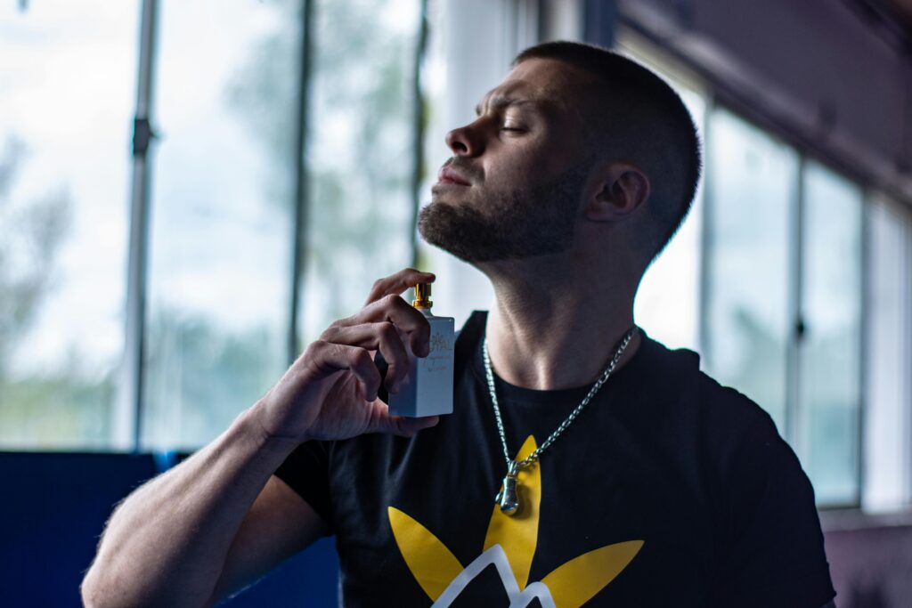 A man enjoying the scent of perfume in a stylish indoor environment, highlighting elegance and style.